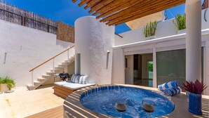 A modern outdoor pool area with a hot tub, a wooden deck, and a staircase leading to an upper level.