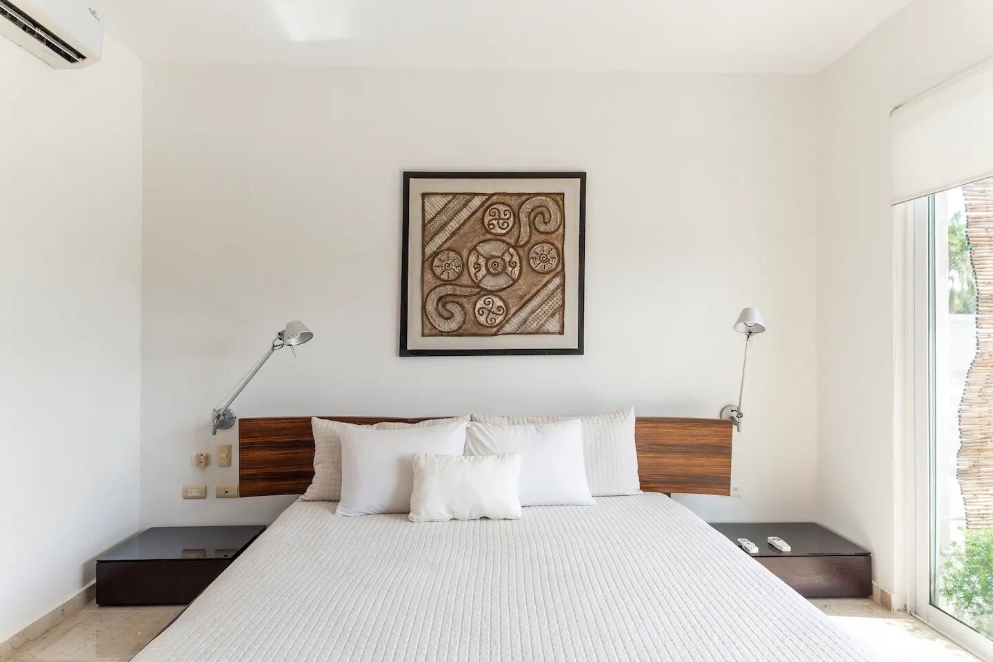 Ein modernes Schlafzimmer mit einem großen Bett, zwei Nachttischen, einem Kopfteil und einem gerahmten Kunstwerk darüber.
