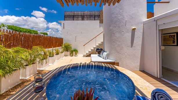 A modern outdoor pool area with a hot tub, a wooden pergola, and a staircase leading to an upper level.