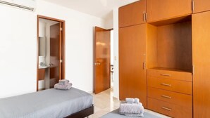 A bedroom with a bed, a wardrobe, and a bathroom visible through an open door.