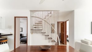 A modern dining area with a wooden table and chairs, a decorative wall with a geometric pattern, and a staircase leading to another room.