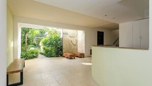 A spacious indoor area with a curved counter, a bench, and a view of a lush garden through a glass door.