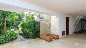 A modern interior with a stone wall, wicker furniture, and a staircase.