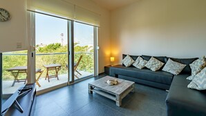 A modern living room with a sofa, a coffee table, and a sliding glass door leading to an outdoor area with a table and chairs.