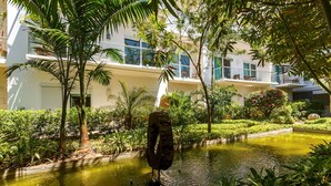 A courtyard with a water feature, surrounded by lush greenery and modern buildings.