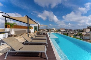 Une piscine sur le toit, avec des chaises longues et une vue sur la ville.