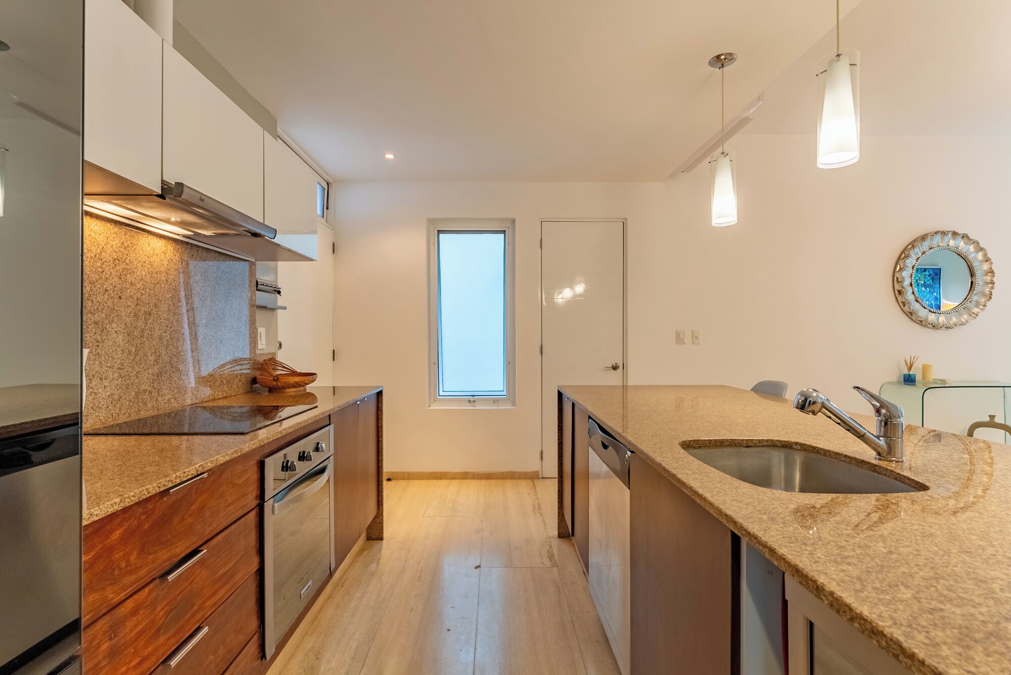 A modern kitchen with granite countertops, stainless steel appliances, and pendant lighting.