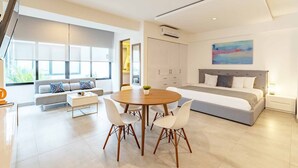Une chambre moderne avec un grand lit, un coin repas avec une table ronde et des chaises, et un salon avec un canapé et un téléviseur.