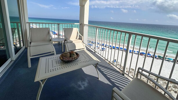 A balcony with a view of the beach, white chairs, a table, and a decorative bowl. - Shoreline Towers 2076 (sleeps 7) Beach Setup Included (March 1-October 31) (Destin)