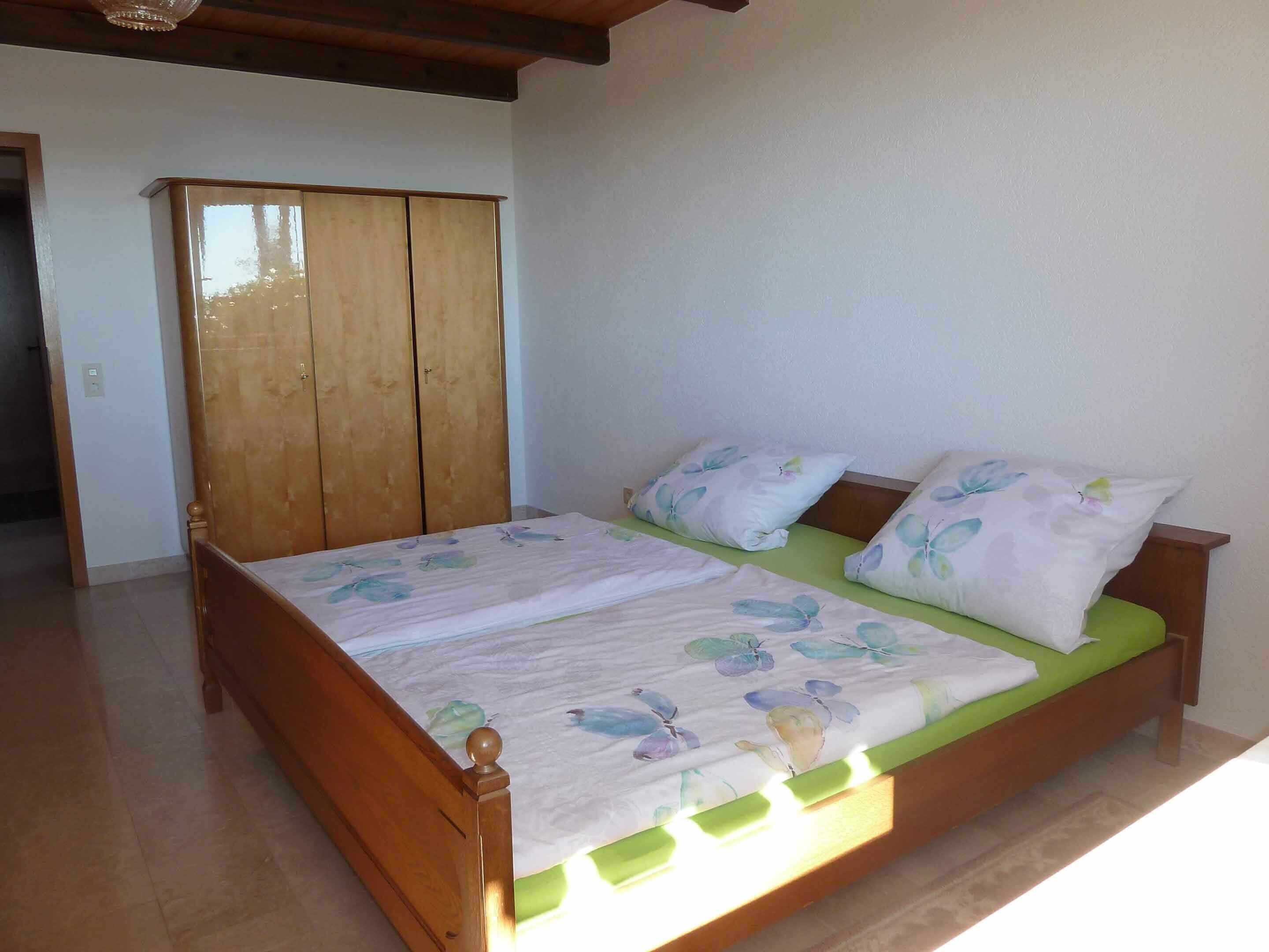 A bedroom with a wooden bed frame, green mattress, and floral bedding.
