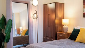 A bedroom with a bed, a wardrobe, a mirror, a floor lamp, and a potted plant. - One Bed Apartment in Waterloo near Southwark (London)
