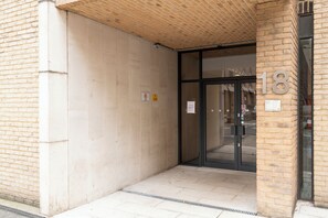 A building entrance with a brick facade, a glass door, and a number '18' sign. - One Bed Apartment in Waterloo near Southwark (London)