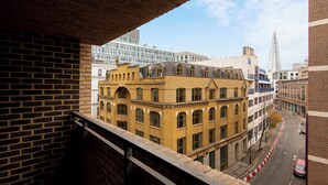 A view of a city street from a balcony with brick buildings, a modern glass building, and a tall spire in the background. - One Bed Apartment in Waterloo near Southwark (London)
