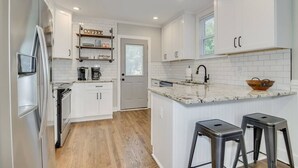 A modern kitchen with white cabinets, a marble countertop, and a built-in oven. - Cozy 2bd in Augusta - The Blue Bungalow (Augusta)