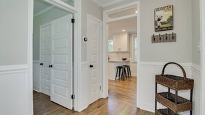 A hallway with white doors, a kitchen area in the background, and a wicker basket on the right. - Cozy 2bd in Augusta - The Blue Bungalow (Augusta)