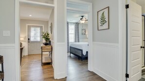 A hallway leading to a bedroom with a bed, a ceiling fan, and a potted plant. - Cozy 2bd in Augusta - The Blue Bungalow (Augusta)