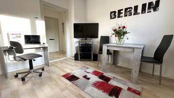 Ein modernes Wohnzimmer mit Fernseher, Schreibtisch und Blumenvase, sowie einem Schild mit der Aufschrift "BERLIN".