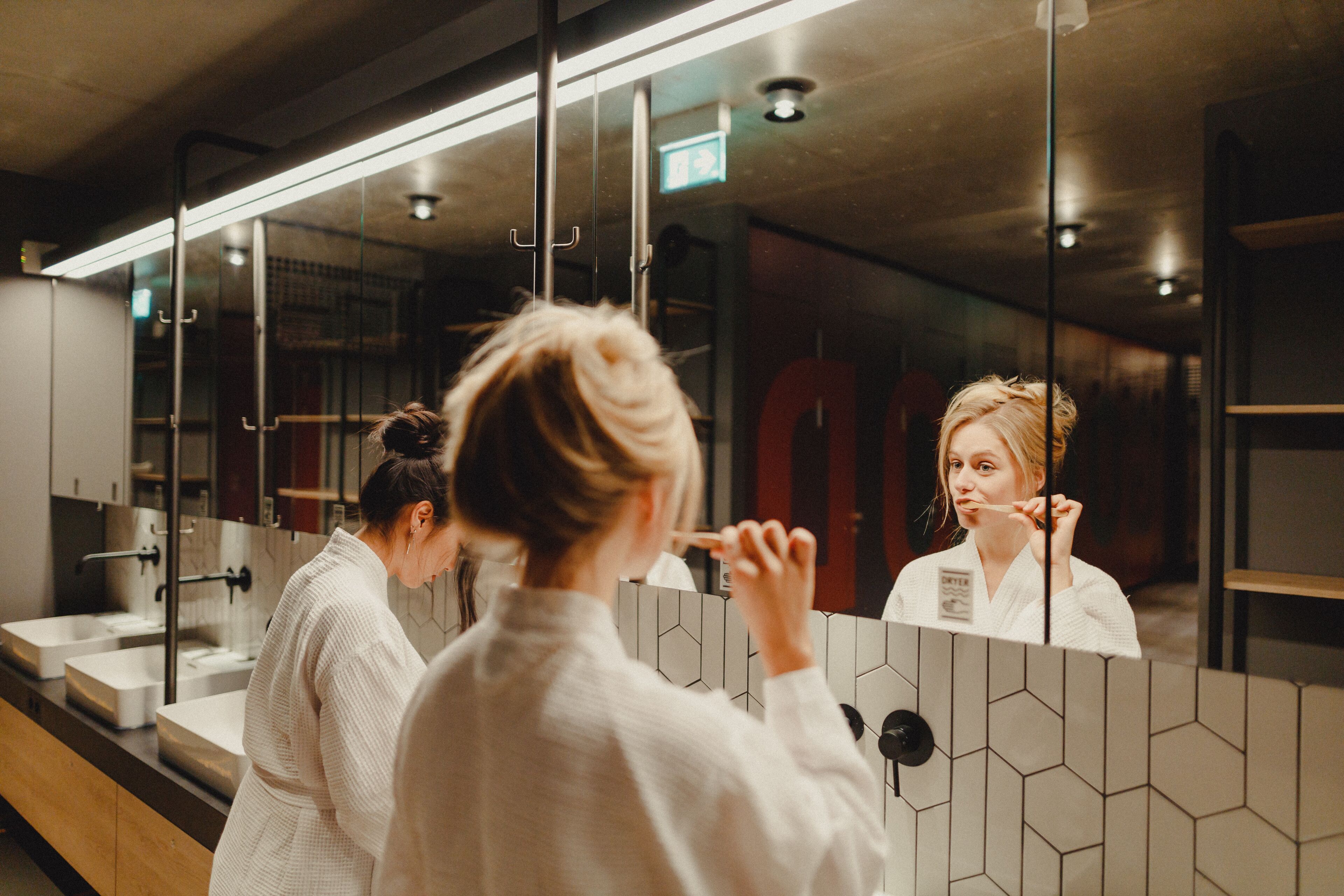 A modern bathroom with a large mirror, a sink, and a towel rack.