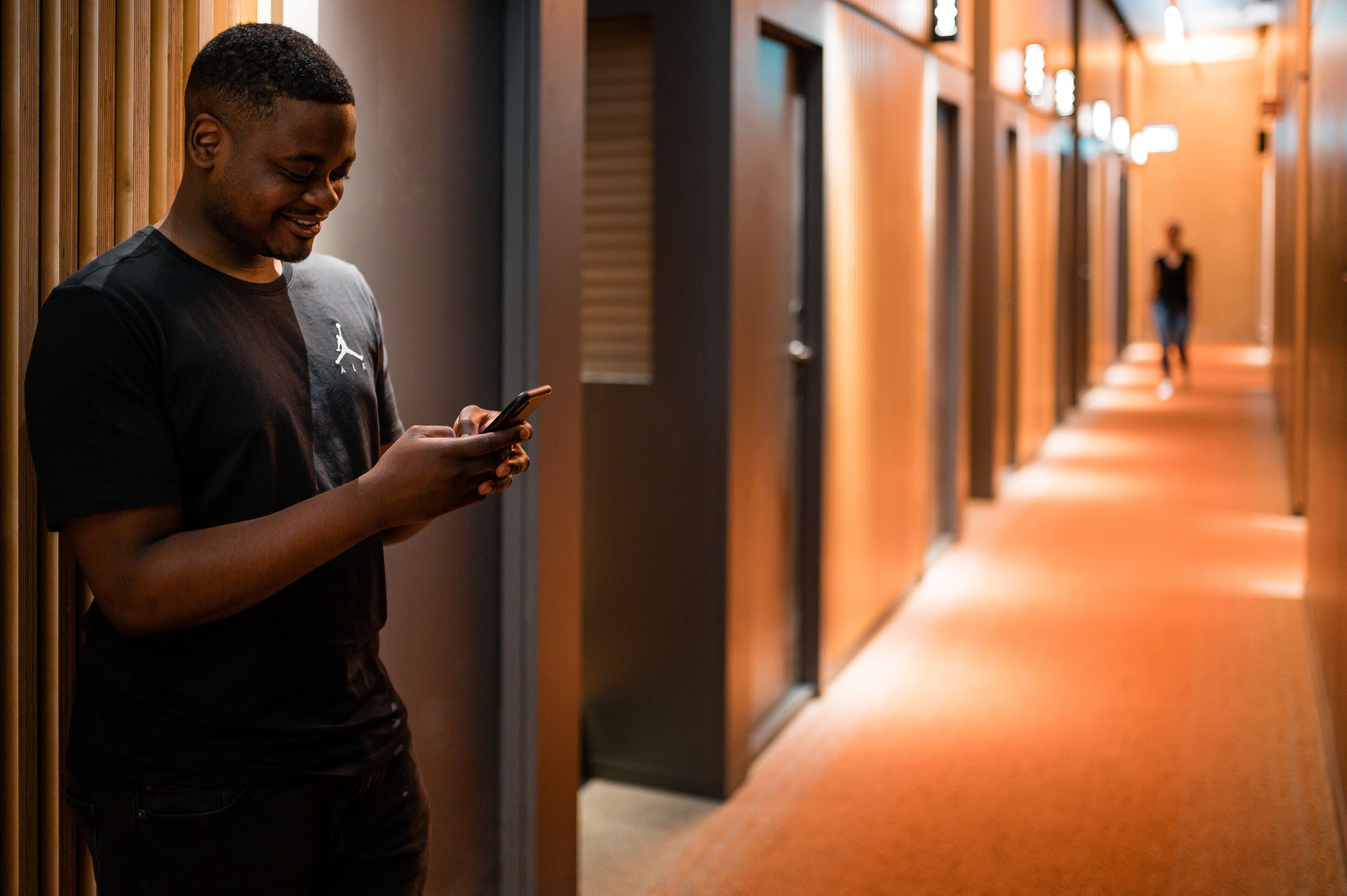 A person standing in a hallway with a corridor extending into the distance.