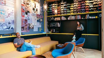 Eine moderne Lounge mit einer Couch, Sesseln und einer Wand, die mit Postern und einer Schallplattenausstellung versehen ist.