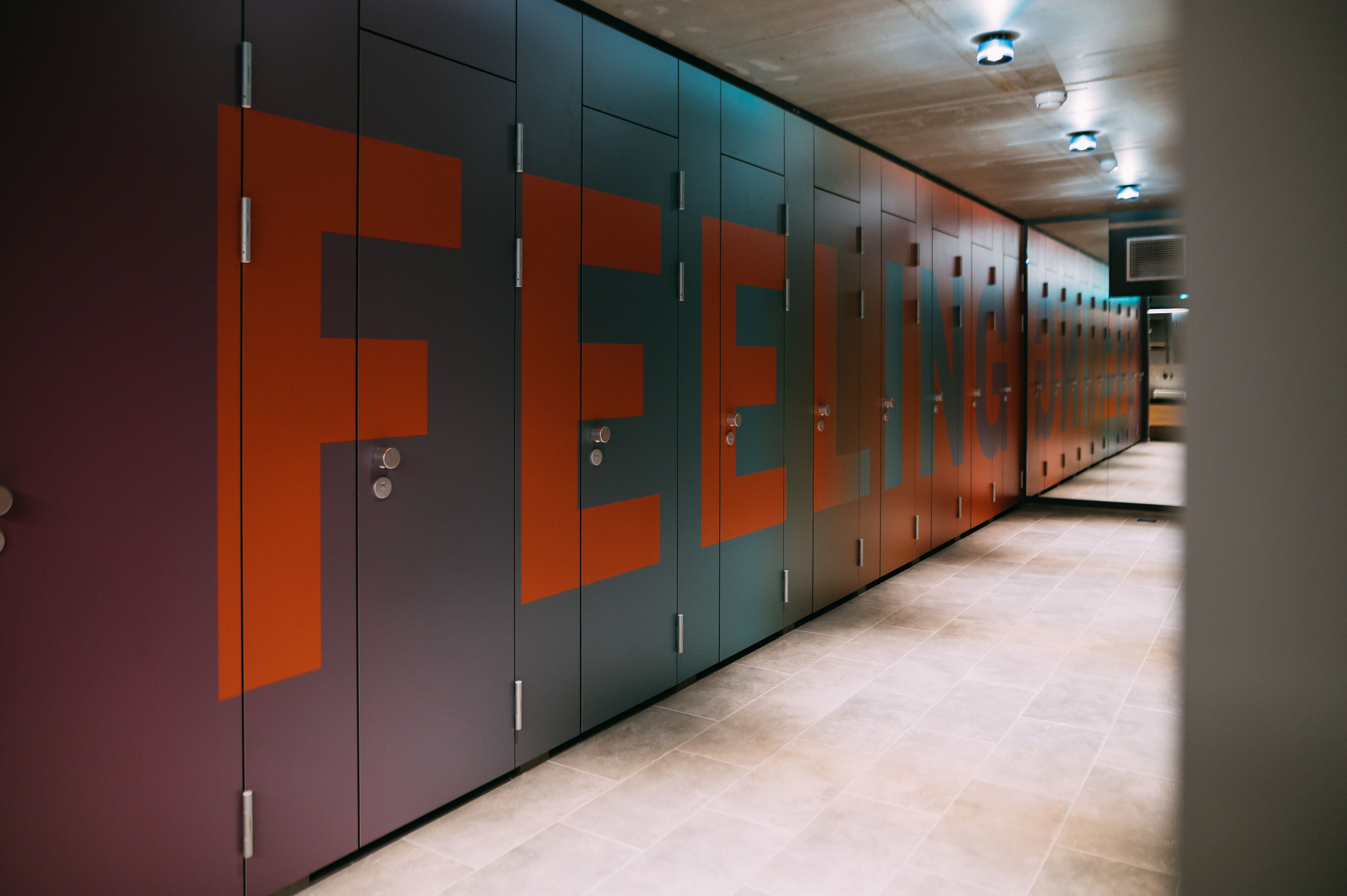 Une rangée de casiers dont les portes sont ornées de grandes lettres formant le mot « FEEN ».