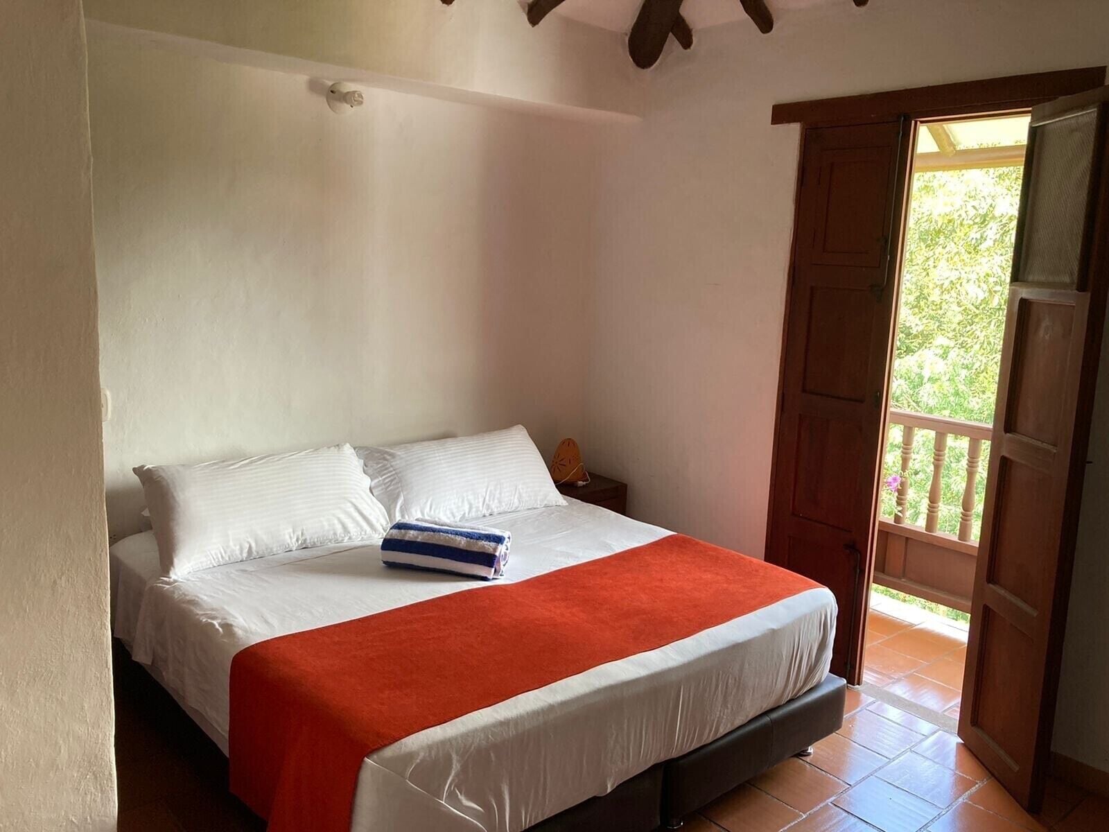 Ein Schlafzimmer mit Bett, Nachttisch, Fenster und Tür.
