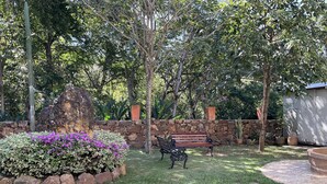 A garden with a stone wall, a wooden bench, and a cactus. - EL RETIRO BARICHARA. APARTMENT 202 OVERLOOKING THE POOL. (Barichara)
