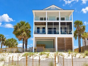 A two-story beachfront house with a balcony, a garage, and a sandy beach in the foreground. - Best pool in the neighborhood! 4 bdrm/4.5 bath gulf front with huge pool. (Port St Joe)