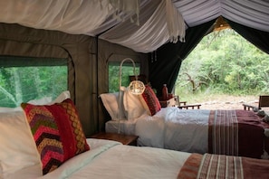 A tent with two beds, a hanging light, and a view of the forest. - Gondwana Game Reserve (Mossel Bay)