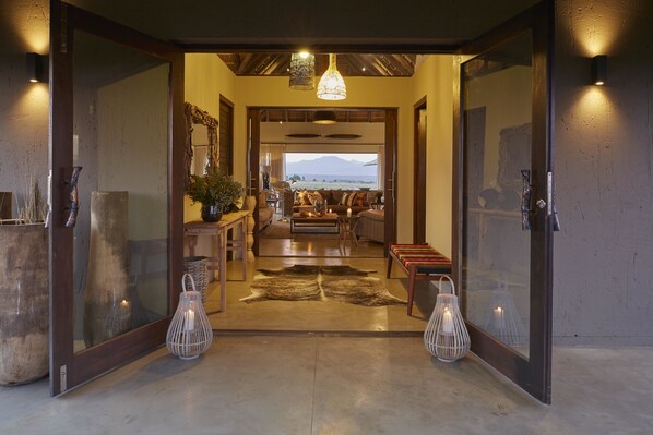 Uma sala de estar ampla com uma grande janela, teto de madeira e um tapete central.