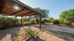 Un espacio al aire libre cubierto con un sendero de grava, pared de piedra y diferentes arbustos y árboles.