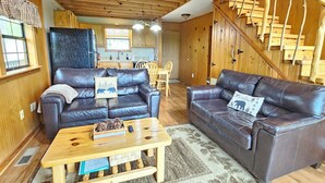 A cozy living room with two leather sofas, a wooden coffee table, and a kitchen in the background. - Private & Secluded w/ Beautiful Views Sunsets ~Hot Tub (Gatlinburg)