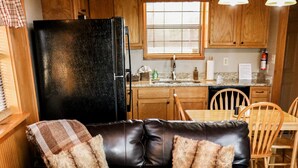 A cozy living room with a leather sofa, wooden coffee table, and a kitchen in the background. - Private & Secluded w/ Beautiful Views Sunsets ~Hot Tub (Gatlinburg)