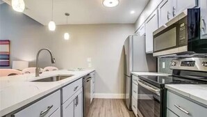 A modern kitchen with stainless steel appliances, white cabinetry, and pendant lighting. - Beach Haven - Unit 1303- Located One Block from the Beach! (Port Aransas)