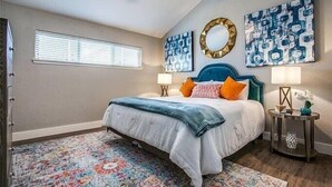 A bedroom with a bed, two bedside tables, a ceiling fan, and artwork on the walls. - Beach Haven - Unit 1303- Located One Block from the Beach! (Port Aransas)