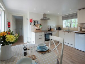 A modern kitchen with white cabinetry, a dining area with a polka dot tablecloth, and a vase of flowers.