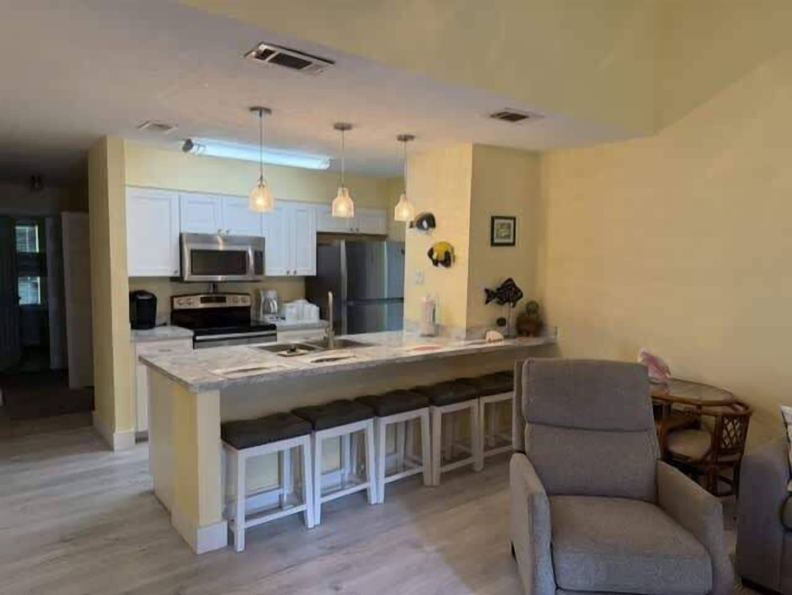 A modern kitchen with a central island, white cabinetry, and pendant lighting.