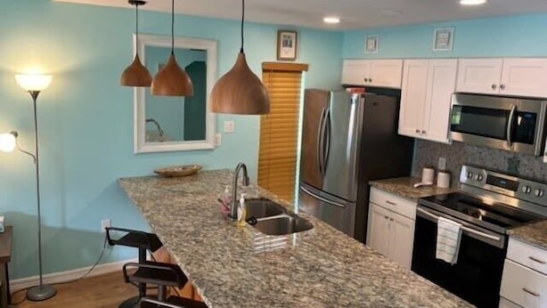 A kitchen with granite countertops, stainless steel appliances, pendant lighting, and white cabinets. - Crabb Shack-One block from Beach-Island Dunes Condo's-#1606 (Port Aransas)