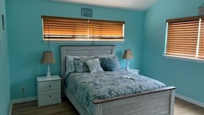 A bedroom with a bed, two bedside tables, and a window with blinds. - Crabb Shack-One block from Beach-Island Dunes Condo's-#1606 (Port Aransas)