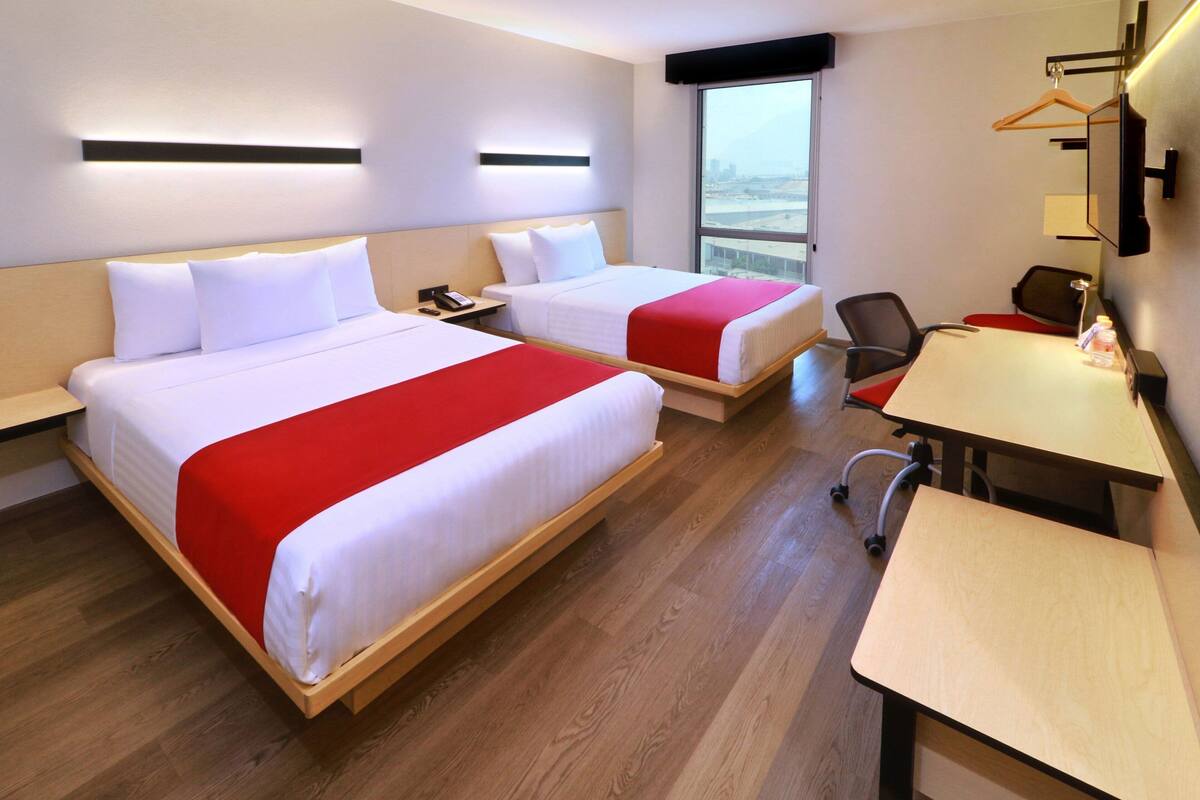 Habitación de hotel con dos camas, un escritorio y una silla.