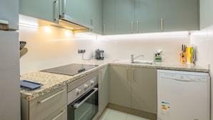 Una cocina moderna con armarios grises, horno empotrado, lavavajillas y encimera de granito.