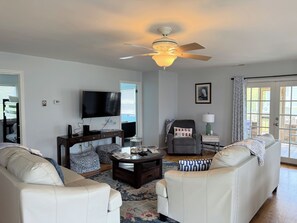 A living room with a ceiling fan, a television, a coffee table, and two sofas.