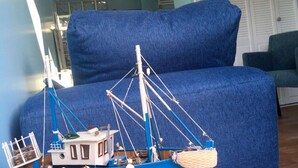 Une maquette de bateau est posée sur un socle bleu dans une pièce aux murs de couleur turquoise et au plancher en bois.