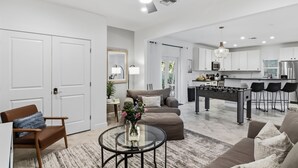 Ein modernes Wohnzimmer mit Sofa, Hocker, Couchtisch und einem Kicker.
