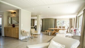 A spacious living area with a sofa, a dining table, and a kitchen area with a staircase.