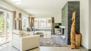 A modern living room with a sectional sofa, a fireplace, and large windows.