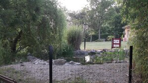 A fenced pond with rocks and trees, a bench, and a sign in the background. - Gîte de l'étanchée (Châtillon-sur-Broué)