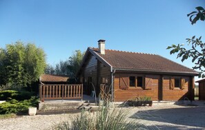 Situated in a serene garden, this cabin features a charming porch and a chimney, surrounded by lush greenery.