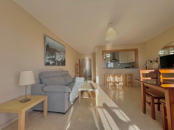 A modern living room with a grey sofa, a coffee table, and a TV area with wooden furniture. - TERRASOL PUERTO BLANCO 4D-10 (Caleta de velez)