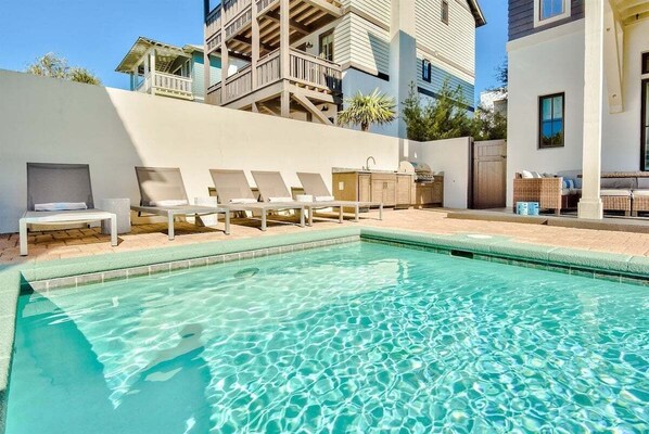 Une piscine avec des chaises longues et, au fond, un bâtiment doté de balcons.